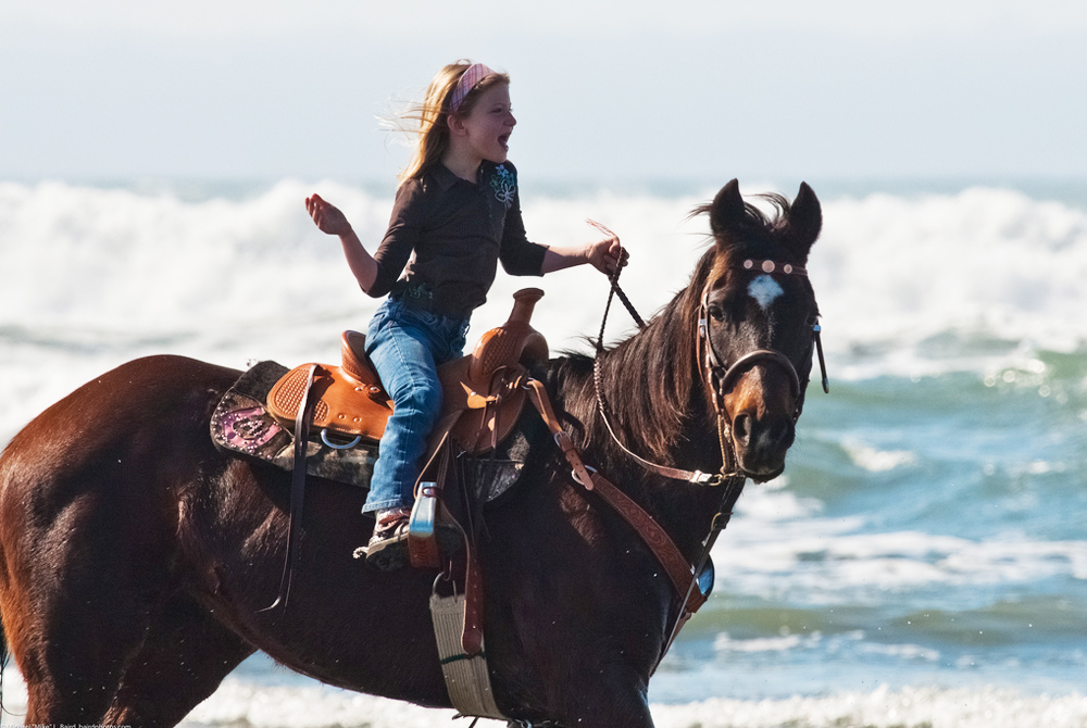 Little girl equestrian riding her horse in the water on Morro St